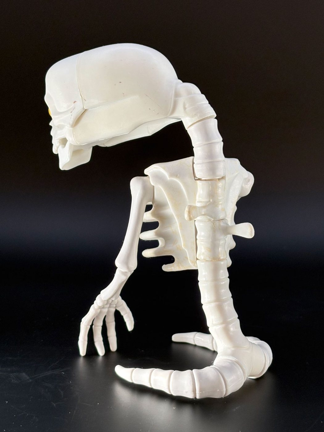 A Kenner Real Ghostbusters Bad-To-The-Bone ghost figure photographed from the side with its skull hinged fully forward on its neck, showing the ribcage open