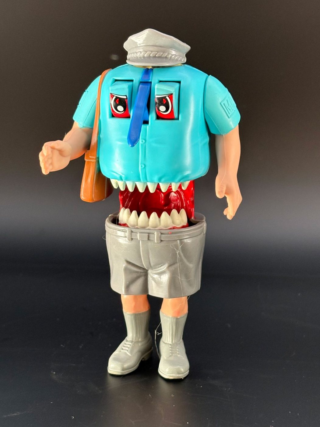 A Kenner Haunted Humans Mail Fraud figure, a mailman in a turquoise shirt and grey cap whose torso has slid up to reveal a fanged monster mouth beneath