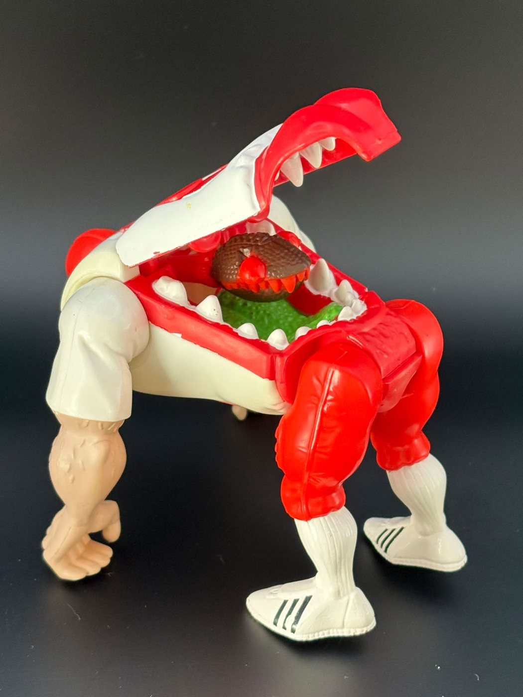 A Kenner Haunted Humans Tombstone Tackle figure with its torso split wide open, a red fanged monster with a green tongue leaning out of the football player's chest