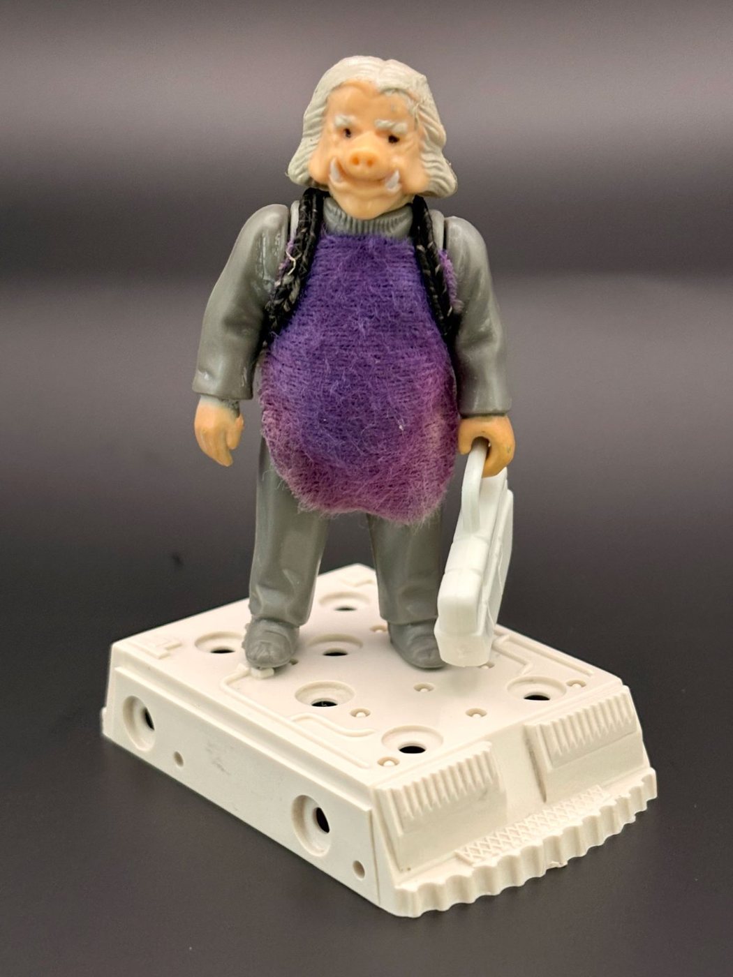 A Kenner Ugnaught figure wearing its purple fabric smock and carrying its white tool case, standing on the Bespin freeze chamber base