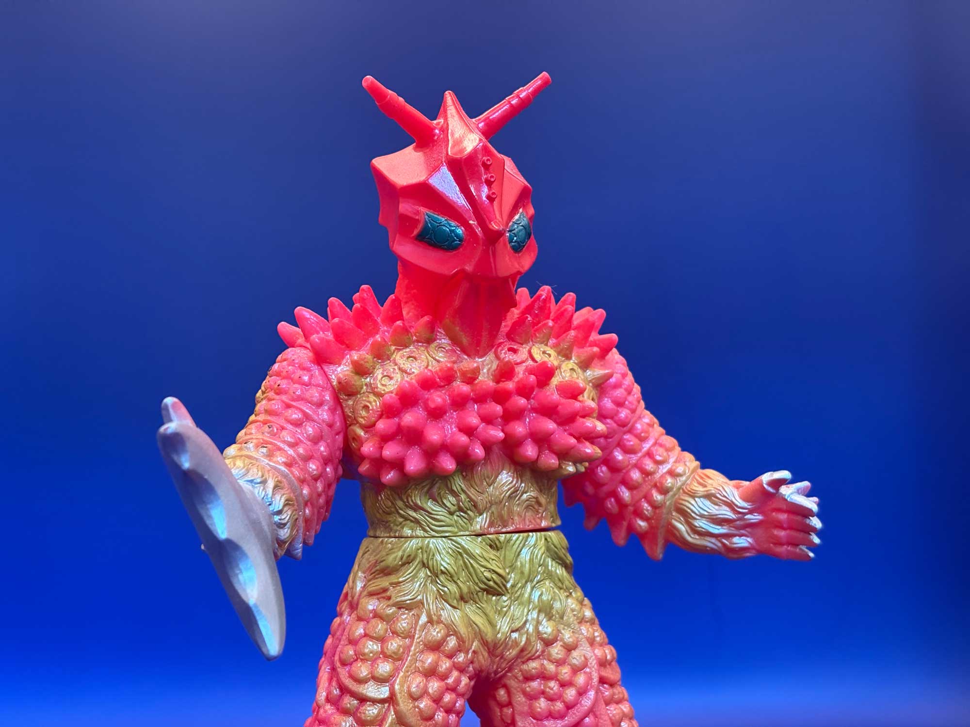 La stessa figura fotografata da vicino di fronte, che mostra le protuberanze rosa del petto contro il ventre oliva e la sfumatura a spruzzo che corre fra i due