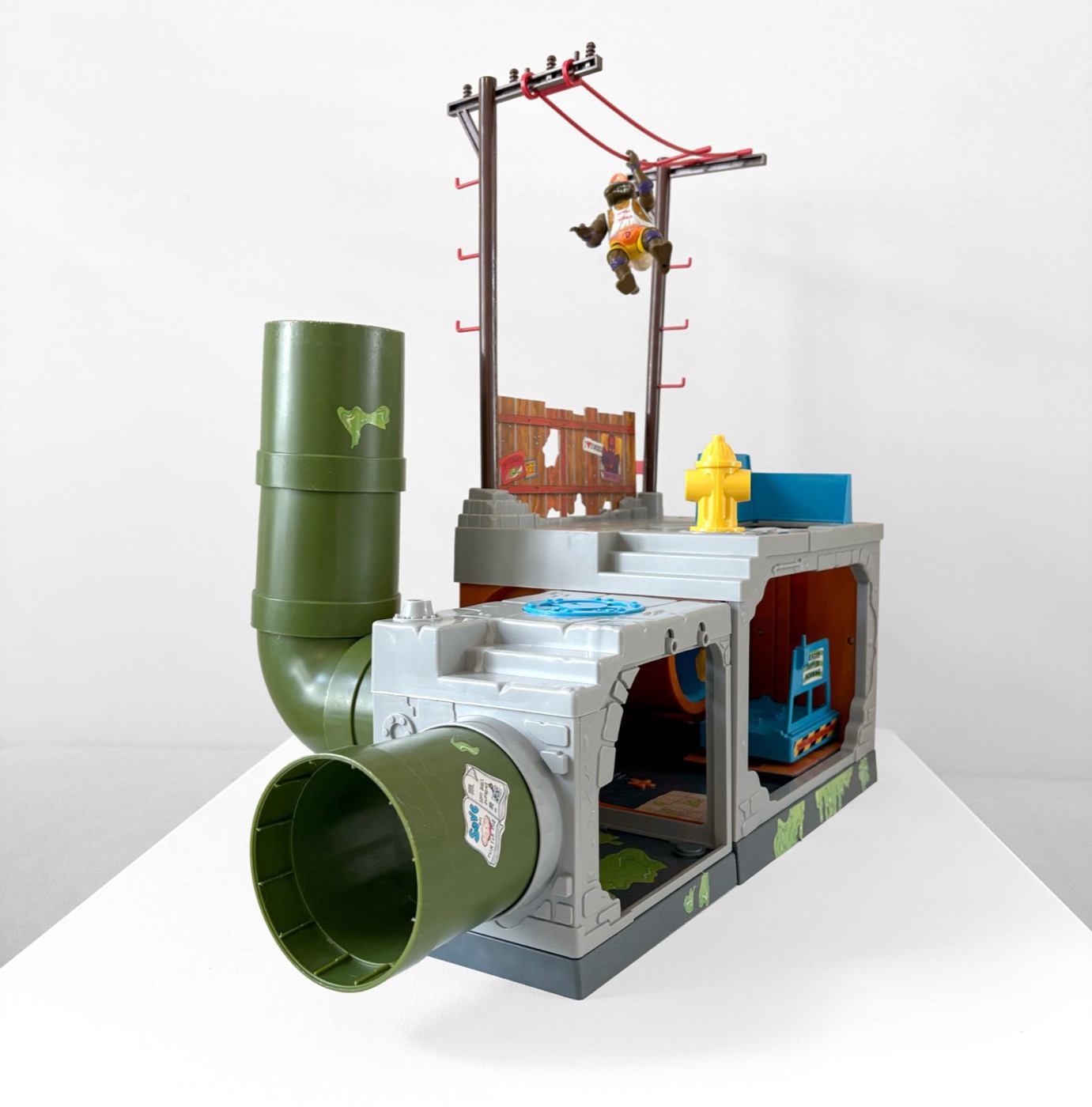 The Playmates Teenage Mutant Hero Turtles Sewer Playset assembled, showing the detachable green sewer pipes, the fire hydrant and the red battle swing strung between two telephone poles